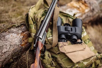 Foto op Aluminium Set militaire jachtuitrusting met geweer in het bos tijdens het jachtseizoen. © kaninstudio