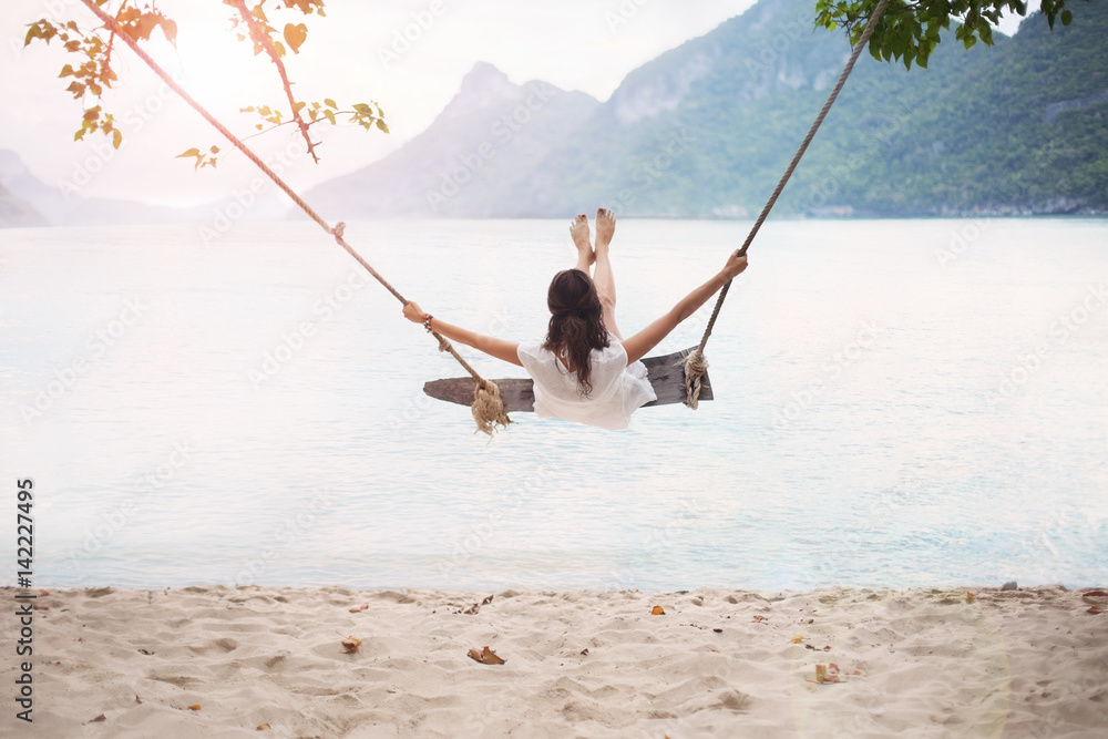 Wall mural Carefree happy woman on swing on beautiful paradises beach