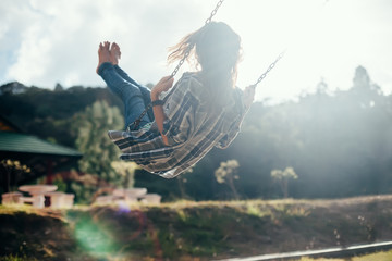 Happy barefoot girl on swing in sun light - obrazy, fototapety, plakaty