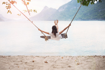 Carefree happy woman on swing on beautiful paradises beach