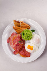 Bacon, poached eggs, mashed peas and toasts on white plate. Grilled rashers and eggs