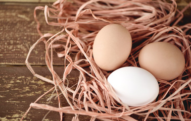 Three chicken eggs on the dry grass