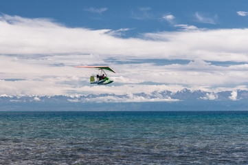 hang-glider hovering over emerald water