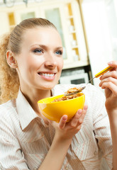 Young smiling woman eating muslin at home