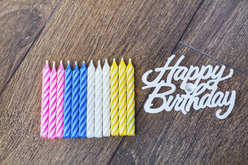 birthday candles and happy birthday sign isolated on a wooden background