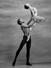 Couple of ballet dancers posing over gray background