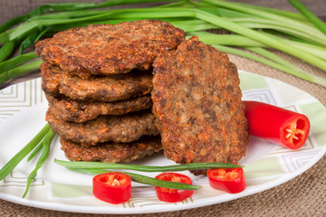 liver pancakes or cutlets with chili pepper and green onions on a wooden background
