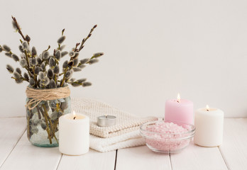 Spa compositiion. Sea salt, towel, sea salt, candles, willow brancher on white wooden background
