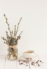 Flowers composition. Grean tea, rose and willow branches on white wooden background