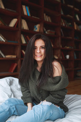 Fototapeta premium Beautiful girl with dark hair sitting on the bed in the morning