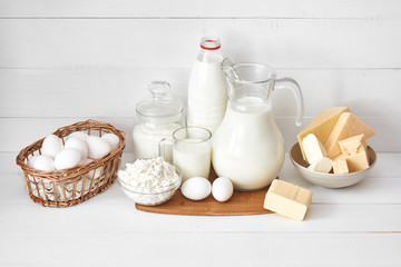 A set of products consisting of milk, butter, curd, cheese and eggs on white wooden table