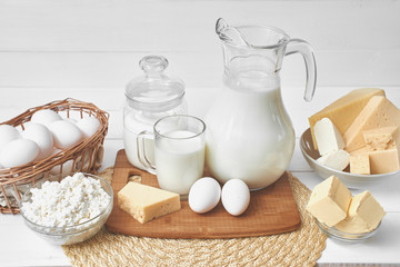 A set of products consisting of milk, butter, curd, cheese and eggs on white wooden table