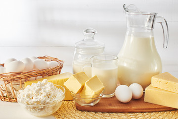 A set of products consisting of milk, butter, curd, cheese and eggs on white wooden table