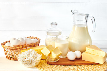 A set of products consisting of milk, butter, curd, cheese and eggs on white wooden table