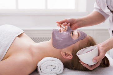 Woman gets face mask by beautician at spa