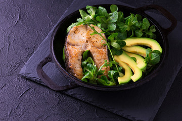 Grilled sheatfish fish steak with avocado, arugula and salad