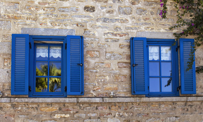 Obraz na płótnie Canvas View of a traditional Bodrum house. Stone walls, blue windows and shutters reflect the architectural style of the region. It shows Aegean / Mediterranean culture and lifestyle
