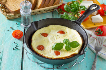 Omelette with tomatoes and suluguni cheese with fresh vegetables on a wooden table. The concept of...