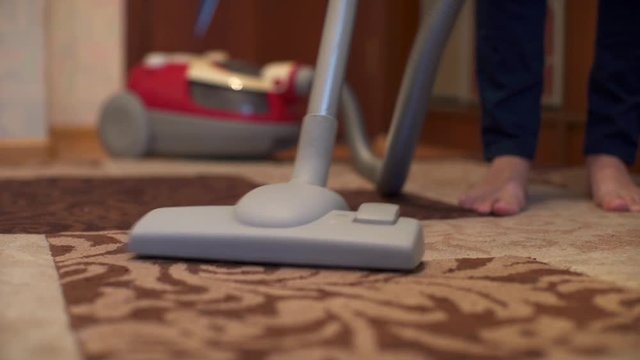 Woman using vacuum cleaner on rug at home in the living room