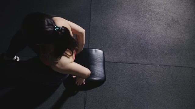 Sportswoman doing situps in gym, top view