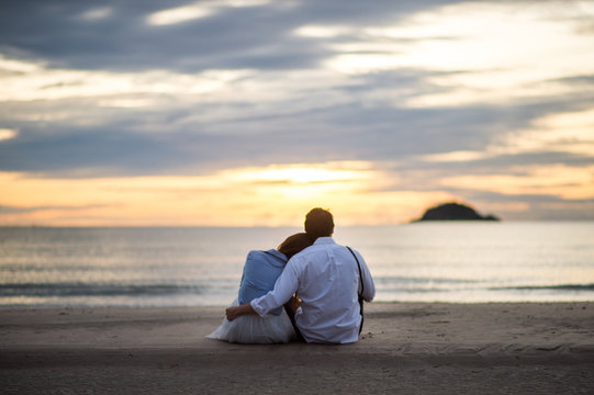 Couple watching sunset in the beach romantic scene