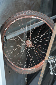 Rusty old bicycle wheel with broken spokes in a cluttered garage