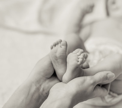 Mother holding tiny foot of newborn baby