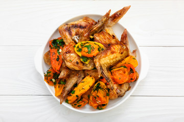 Grilled chicken wings, with vegetables. Wooden white table.  
