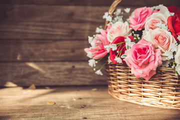 vintage flower rose in the basket on old wood background.