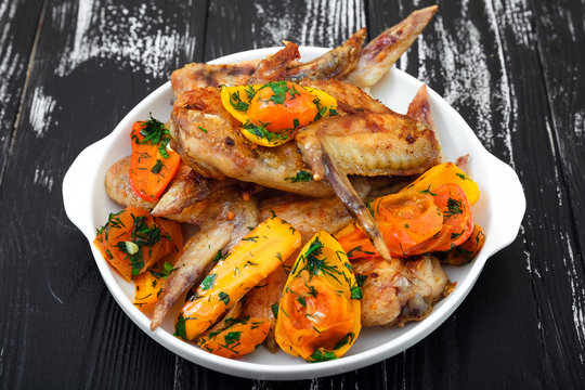 Grilled chicken wings, with vegetables. Wooden table. 
