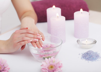 Obraz na płótnie Canvas Nail Care. Closeup Of Beautiful Woman Hands With Natural Nails In Beauty Salon. Female Soaking Fingernails In Transparent Glass Bowl Full Of Water Indoors. Spa Manicure Concept. High Resolution