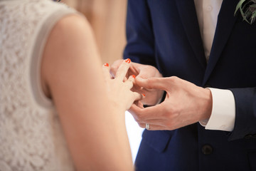 The groom puts the ring on the finger of the bride