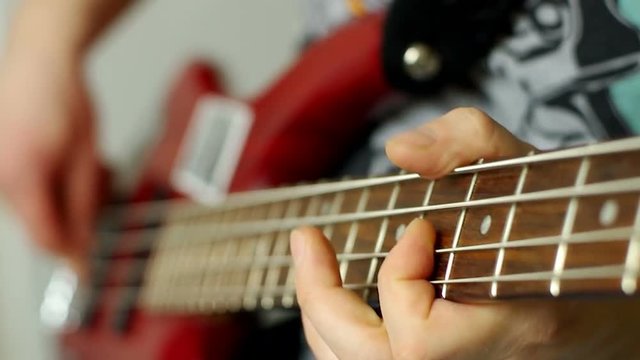 Man playing on bass guitar. Selective focus on fingers