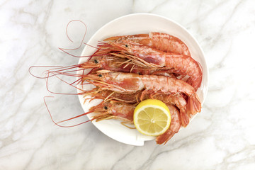 Raw shrimps with slice of lemon on plate