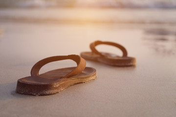 Abstract brown shoes on beach and sand with sunset background, vacation and holiday concept, with copy space