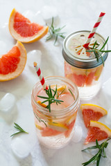 Refreshing summer drink with grapefruit and rosemary on a stone background. The concept of eating vegetarians, fresh vitamins, a homemade refreshing fruit drink.