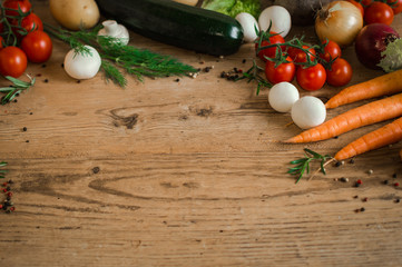 Organic vegetarian diet. Fresh vegetables on a wooden background table. Scattered pepper and sprigs of oregano.