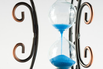 Fototapeta premium Vintage hourglass with curls patterns on the edges. Presuposes (perespevshie) blue sand in them.