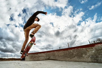A young skateboarder makes Wallie in a skatepark, jumping on a skateboard into the air with a coup © yanik88
