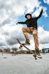 A young skateboarder makes Wallie in a skatepark, jumping on a skateboard into the air with a coup © yanik88
