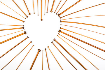 Heart symbol made of wooden knitting needles on white background. © vejaa