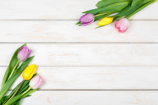 Bunch of colored tulips lying on a white wooden background