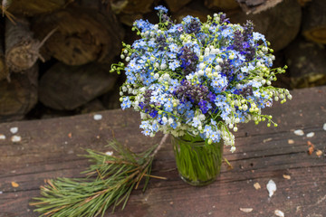 Fototapeta na wymiar Beautiful bright blue and white bouquet with wild flowers on wooden table outdoors. Closeup photo
