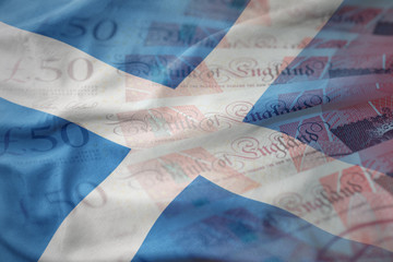colorful waving national flag of scotland on a pounds money banknotes background. finance concept