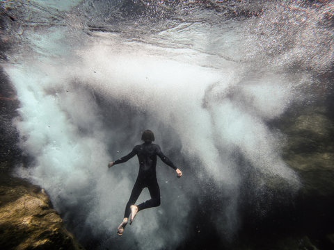 man floating in front of underwater waterfall
