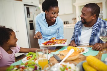 Happy woman serving food to the family