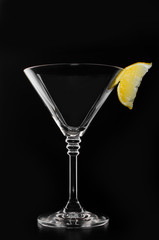 A glass with vermouth and ice cube on a black background