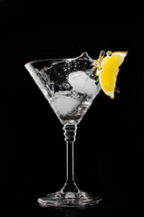 A glass with vermouth and ice cube on a black background