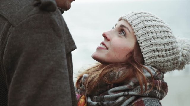 Young couple looking at the sea, walking along the beach, coat and hat, Baltic or Iceland cold weather close-up