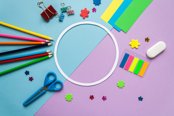 round frame with stationery on blue and violet background. flat lay.